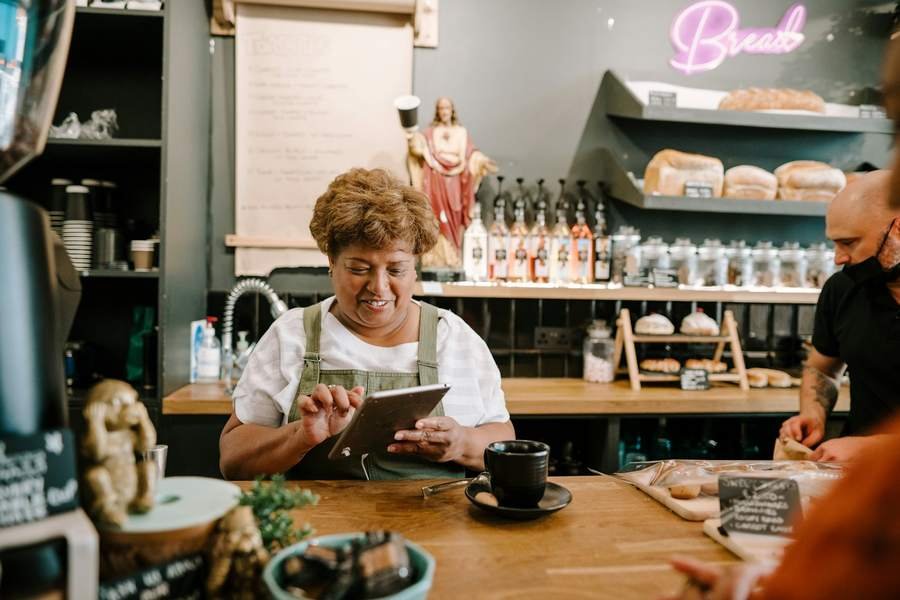 La dueña de una panadería revisa sus ventas en la tablet, detrás del mostrador